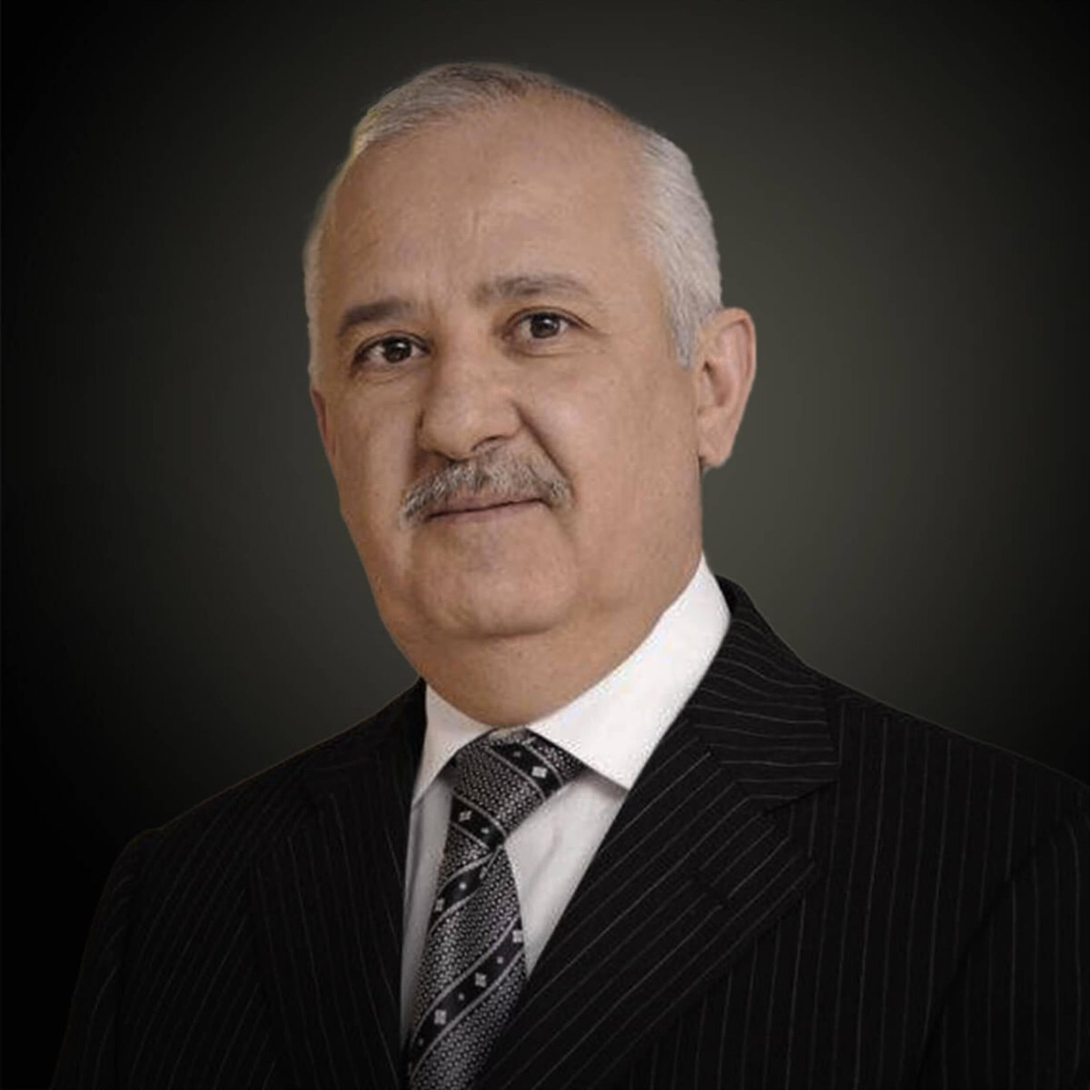 Formal studio portrait of Anas Sefrioui in a pinstriped suit against a dark background