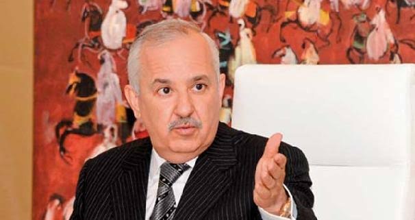 Anas Sefrioui gesturing during a discussion, with artwork on the wall behind him